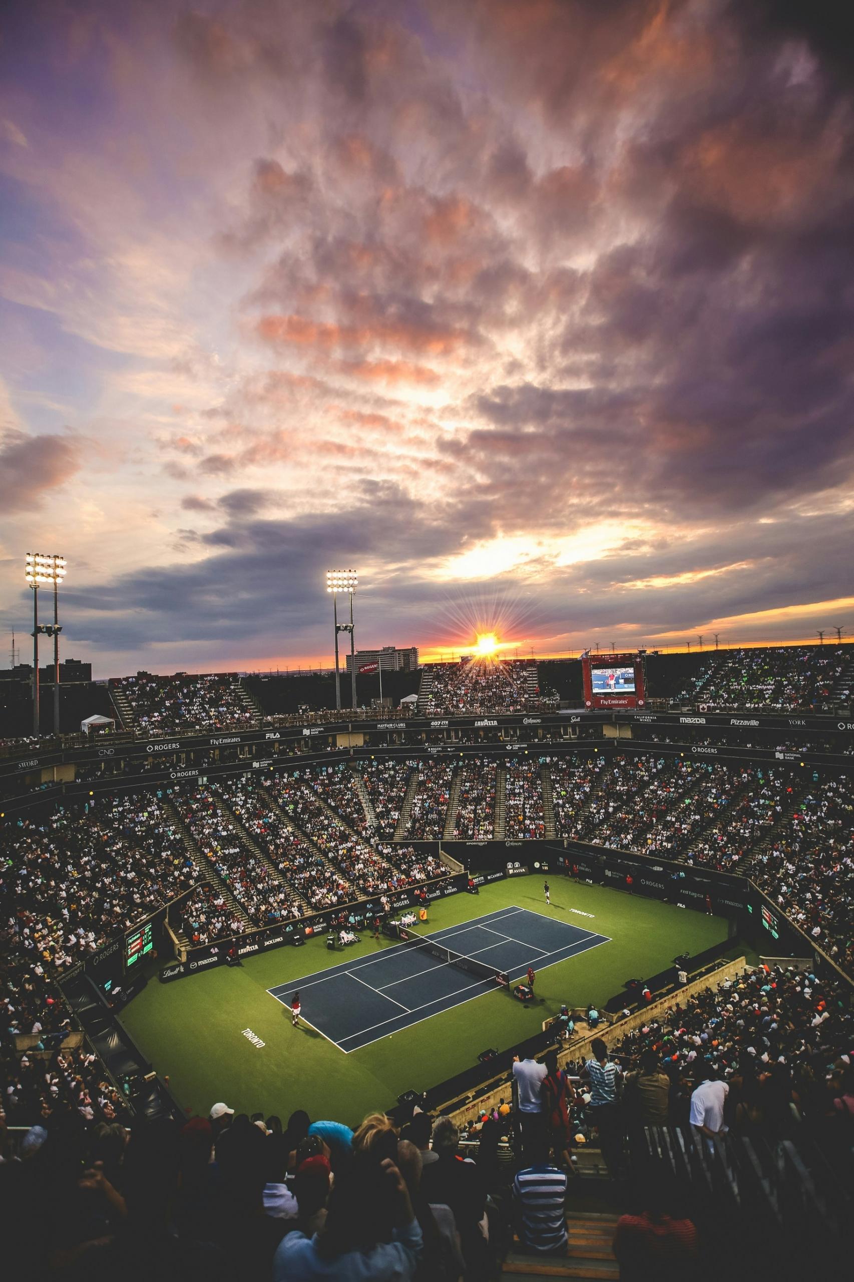 overhead view of a tennis court with spectators during an evening match