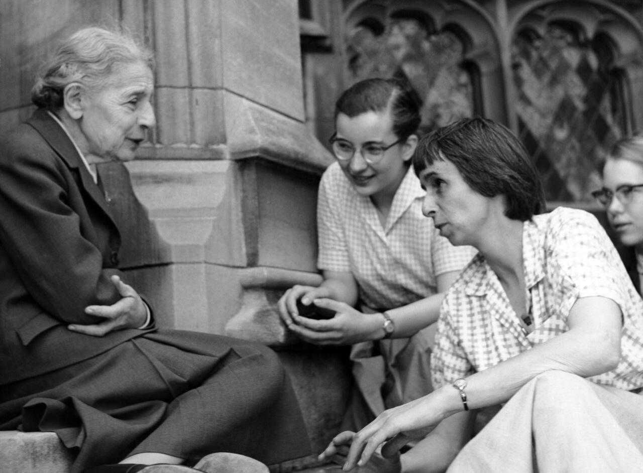 Lise Meitner sitting outside with students, in 1959.